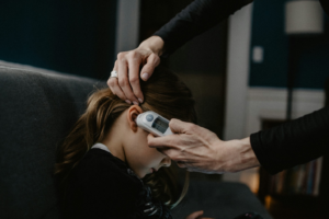 A mother using a thermometer to check her child's temperature.