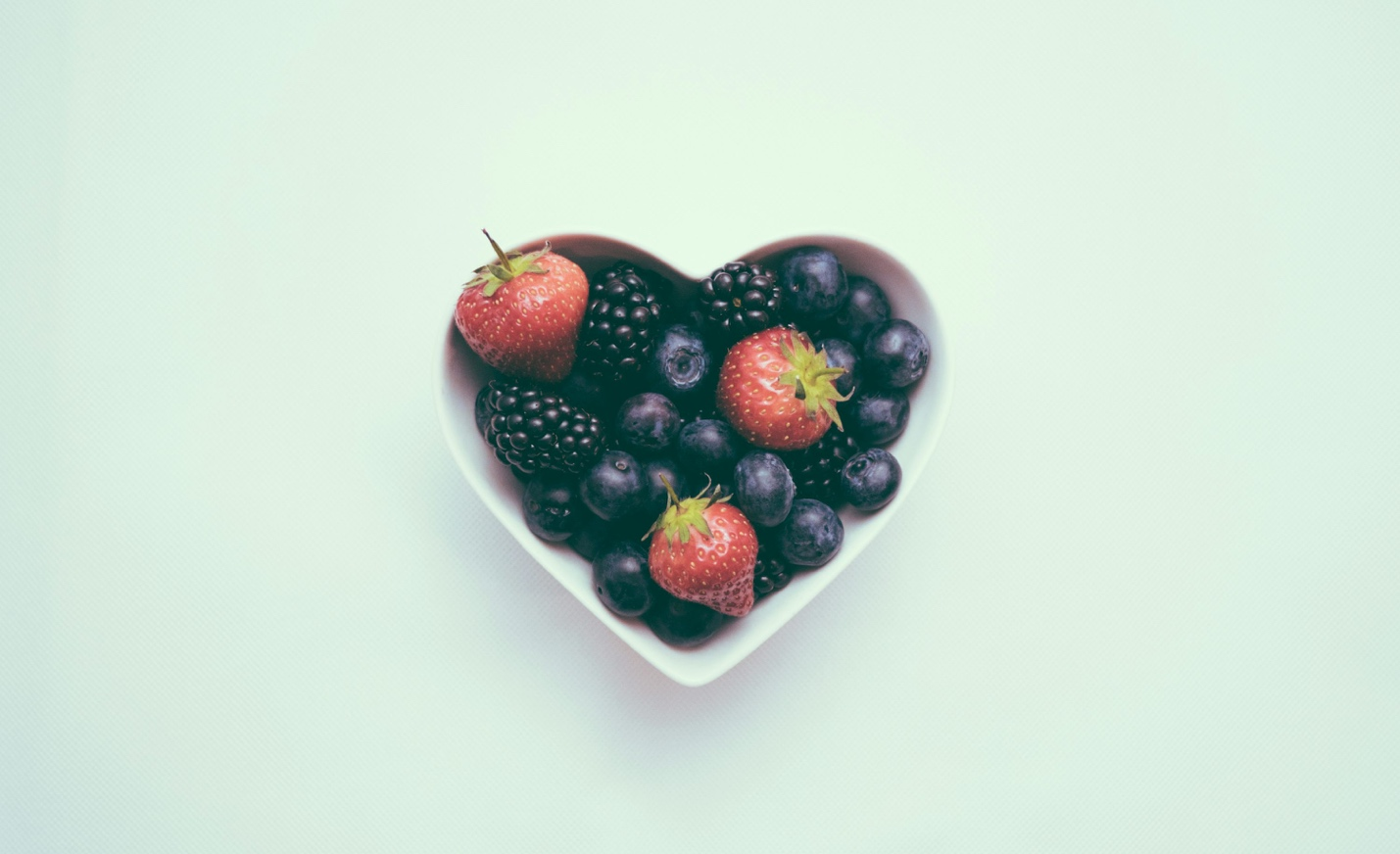 A heart-shaped bowl filled with fresh berries.