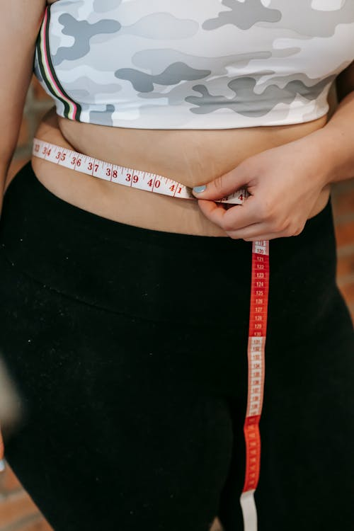 A woman measuring waistline with a tape measure.