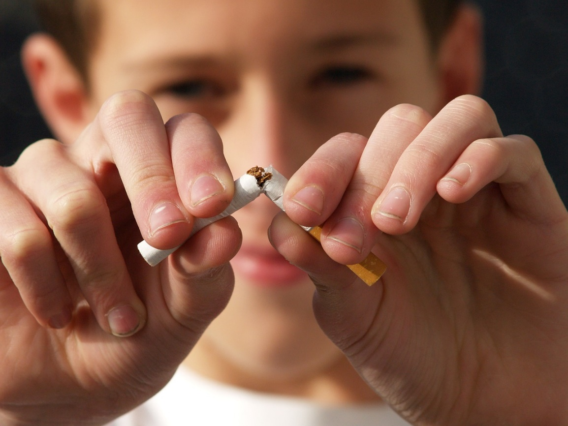A young person breaking a cigarette, symbolizing the first step to quitting smoking.