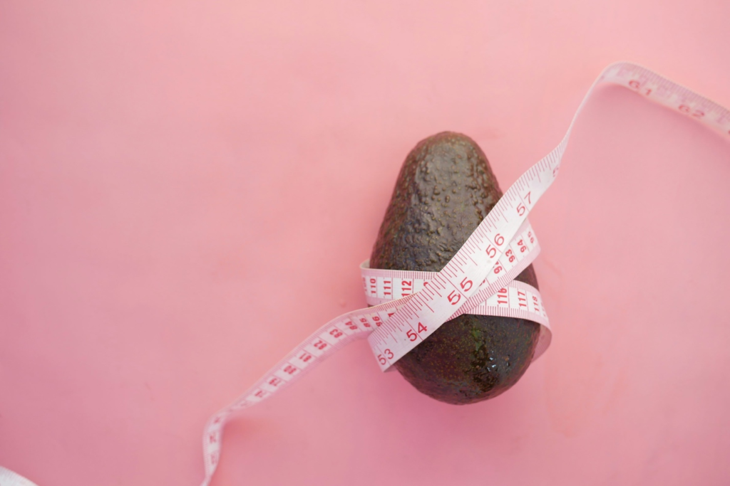 An avocado wrapped with a measuring tape, symbolizing weight management or healthy eating.