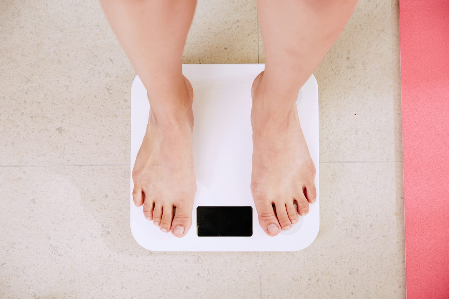 A person's feet standing on a bathroom scale, symbolizing weight loss or health goals.